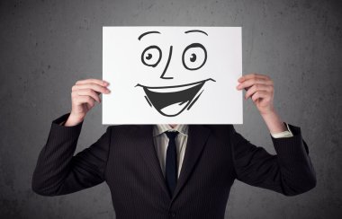 empresario sosteniendo una cartulina con cara sonriente en él en frente 