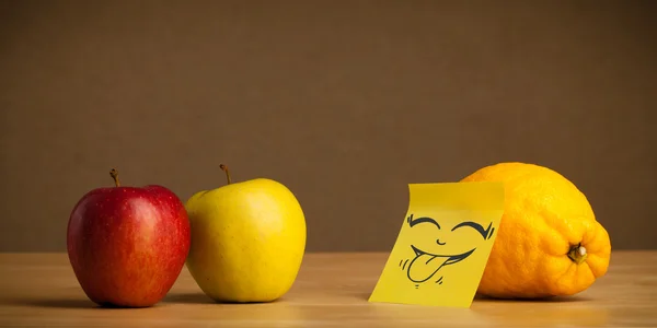 Lemon with post-it note sticking out tongue to apples — Stock Photo, Image