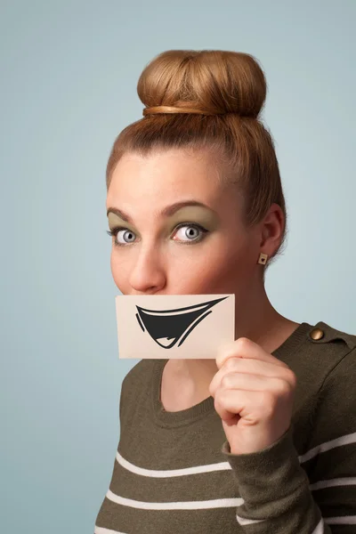 Happy cute girl holding paper with funny smiley drawing — Stock Photo, Image