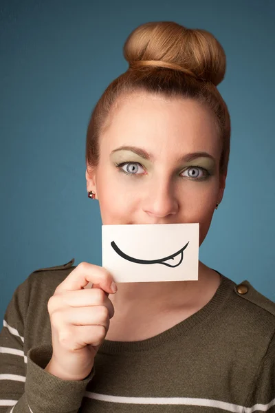 Chica bastante joven sosteniendo la tarjeta blanca con dibujo sonrisa —  Fotos de Stock