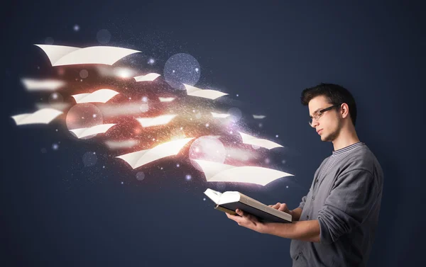 Young guy reading a book with flying sheets coming out of the bo — Stock Photo, Image