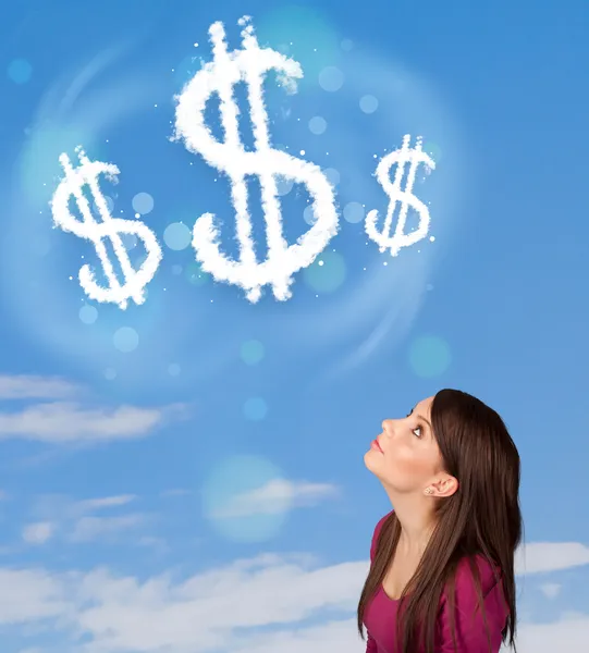 Young girl pointing at dollar sign clouds on blue sky — Stock Photo, Image