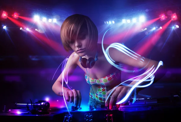 Disc jockey girl playing music with light beam effects on stage — Stock Photo, Image