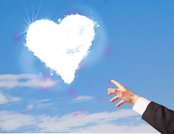 Hand pointing at white heart cloud on blue sky — Stock Photo, Image