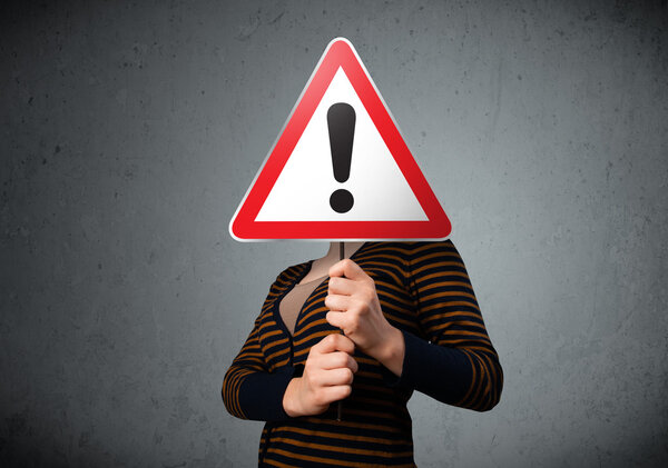 Молодая женщина держит восклицательный дорожный знак