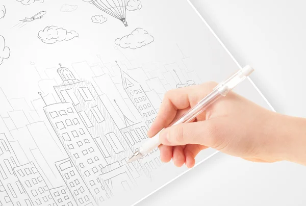 En person som ritning skiss av en stad med ballonger och moln på en — Stock fotografie