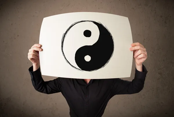 Businessman holding a paper with a yin-yang on it in front of hi — Stock Photo, Image