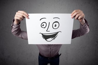 empresario sosteniendo una cartulina con cara sonriente en él en frente 