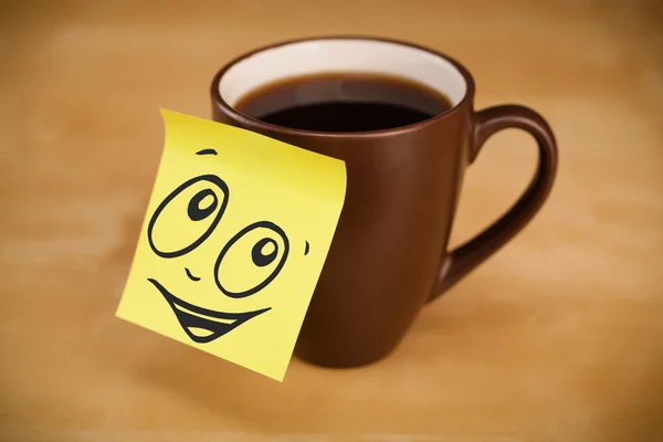 Post-it opmerking met smileygezicht gevezen op cup — Stockfoto