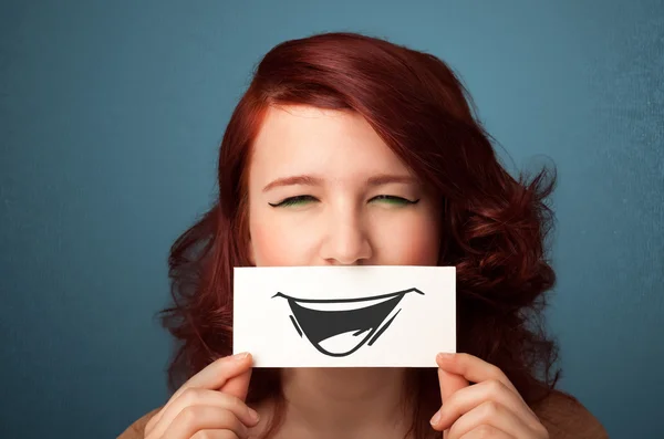 Happy cute girl holding paper with funny smiley drawing — Stock Photo, Image