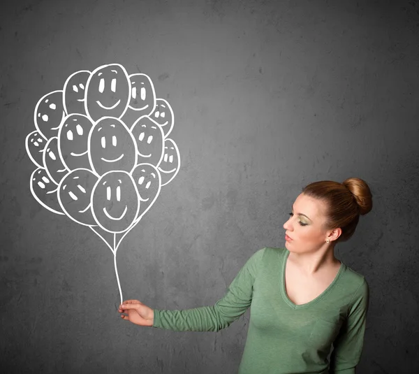 Woman holding a bunch of smiling balloons — Stock Photo, Image