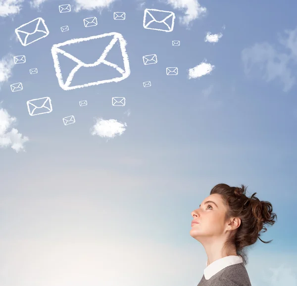 Chica joven mirando el símbolo de correo nubes en el cielo azul — Foto de Stock