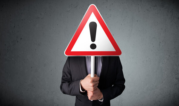 Businessman holding an exclamation road sign
