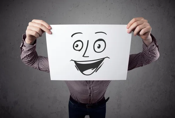 Businessman holding a cardboard with smiley face on it in front — Stock Photo, Image