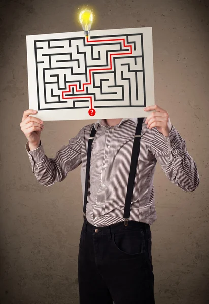 Businessman holding a paper with a labyrinth on it in front of h — Stock Photo, Image