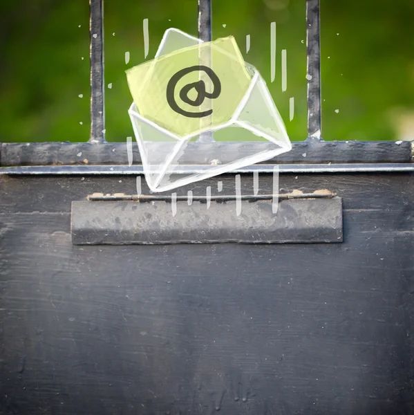 Envelope with email sign dropping into mailbox — Stock Photo, Image