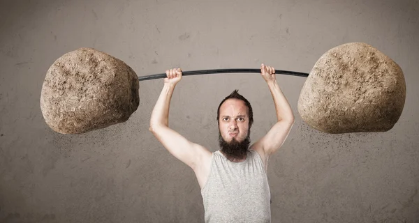 Skinny guy lifting large rock stone weights — Stock Photo, Image