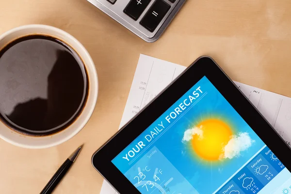 Tablet PC que muestra el pronóstico del tiempo en pantalla con una taza de café — Foto de Stock