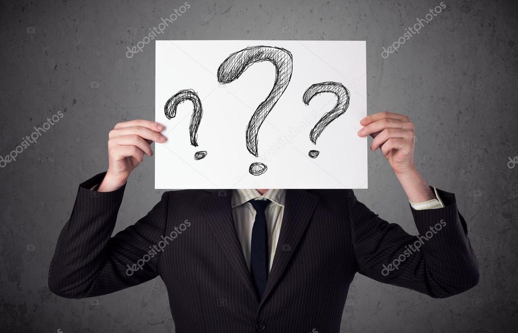 Businessman holding a paper with question marks in front of his 