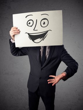 empresario sosteniendo una cartulina con cara sonriente en él en frente 