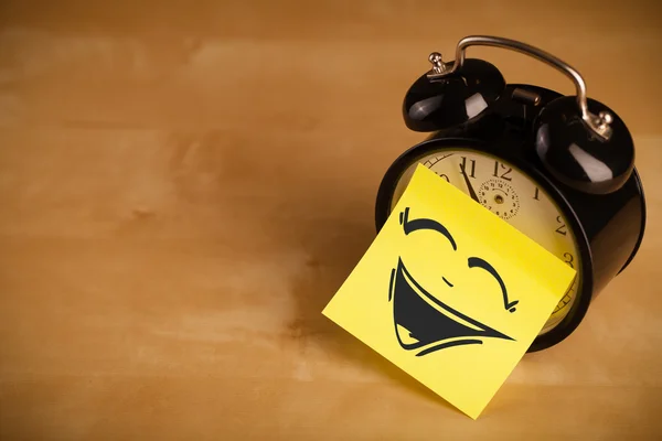 Post-it note with smiley face sticked on clock — Stock Photo, Image