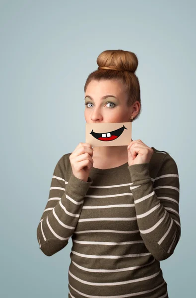 Happy pretty woman holding card with funny smiley — Stock Photo, Image