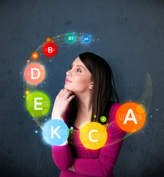 Young woman thinking with vitamins circulation around her head — Stock Photo, Image