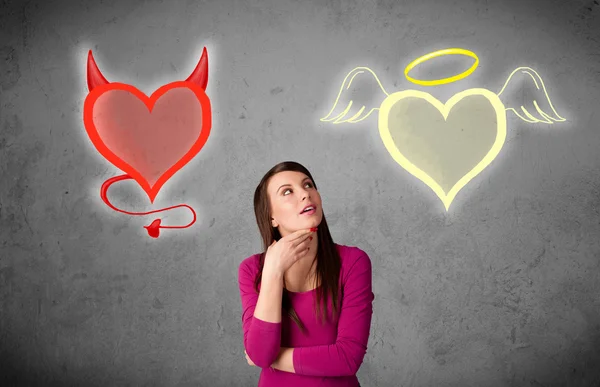 Woman standing between the angel and devil hearts — Stock Photo, Image