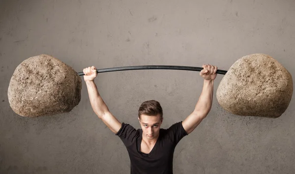 Uomo muscolare sollevamento grandi pesi di pietra di roccia — Foto Stock