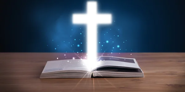 Open holy bible with glowing cross in the middle — Stock Photo, Image