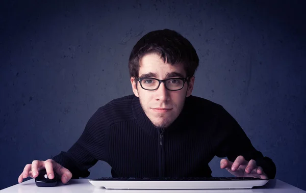 Haker pracujący z klawiaturą na niebieskim tle — Zdjęcie stockowe