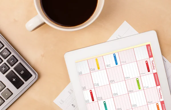 Tablet pc kalendarz wyświetlone na ekranie przy filiżance kawy na d — Zdjęcie stockowe