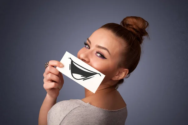 Happy cute girl holding paper with funny smiley drawing — Stock Photo, Image