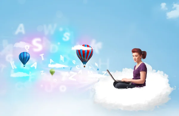 Genç bir kadın dizüstü bilgisayarla bulutlarda oturuyor — Stok fotoğraf