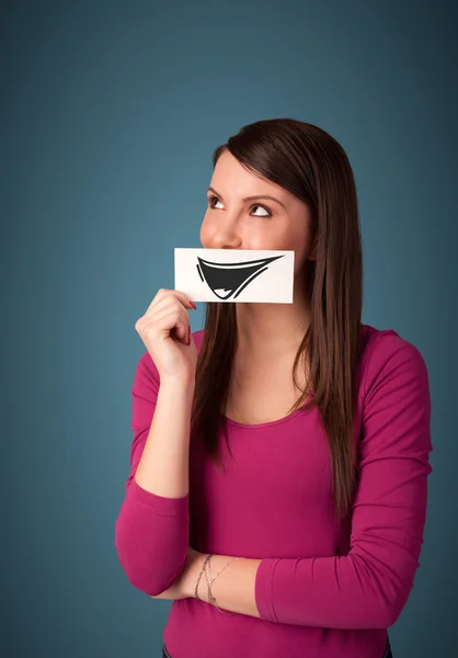 Happy cute girl holding paper with funny smiley drawing — Stock Photo, Image