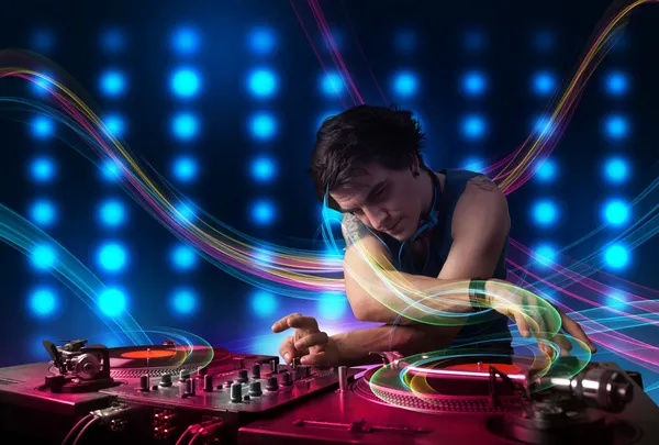 Jovem Dj misturando registros com luzes coloridas — Fotografia de Stock