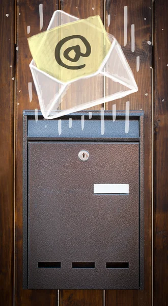 Envelope with email sign dropping into mailbox — Stock Photo, Image