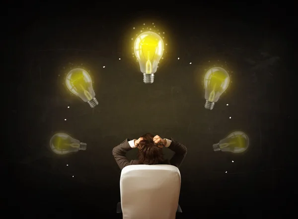 Бизнесмен сидит с лампочками над головой — стоковое фото