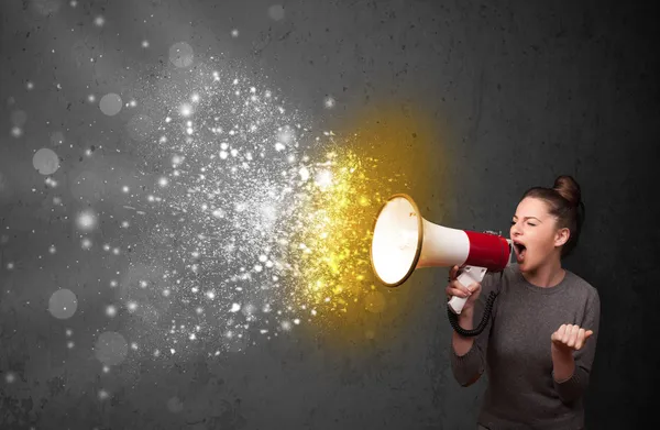 Woman shouting into megaphone and glowing energy particles explo — Stock Photo, Image
