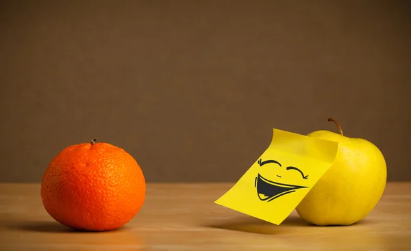 Apple with post-it note laughing on orange — Stock Photo, Image