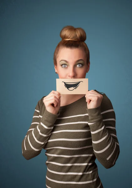 Happy cute girl holding paper with funny smiley drawing — Stock Photo, Image