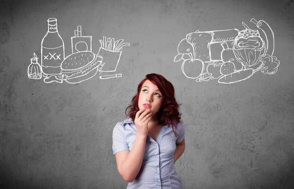 Mujer que se interpone entre alimentos saludables y no saludables — Foto de Stock