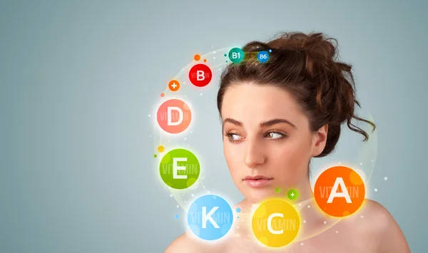 Pretty young girl with colorful vitamin icons and symbols — Stock Photo, Image