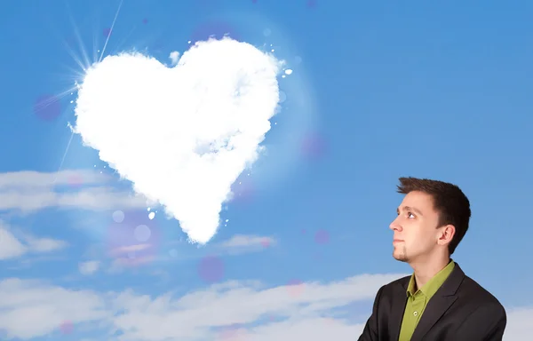 Schöner Mann mit Blick auf weiße Herzwolken am blauen Himmel — Stockfoto