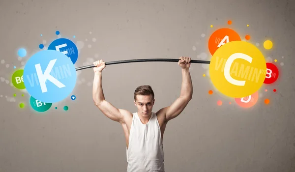 Muscular man lifting colorful vitamin weights — Stock Photo, Image