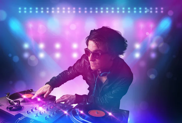 Disco jockey misturando música em toca-discos no palco com luzes e — Fotografia de Stock