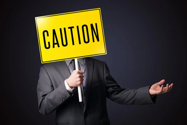 Businessman holding a caution sign — Stock Photo, Image