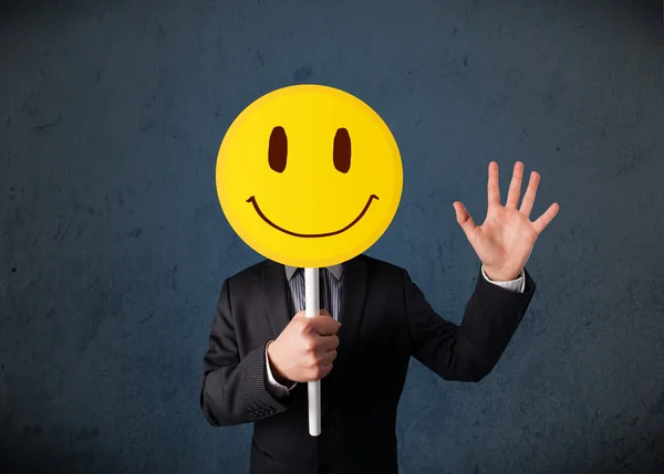 Businessman holding a smiley face emoticon — Stock Photo, Image