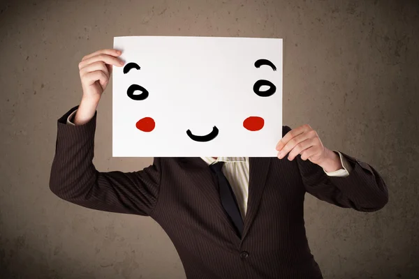 Geschäftsmann hält einen Karton mit einem Smiley darauf — Stockfoto
