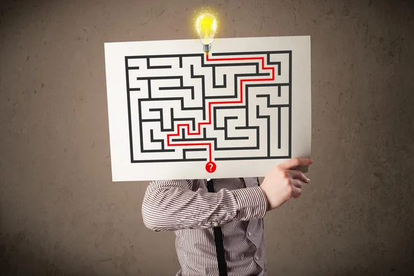 Businessman holding a paper with a labyrinth on it in front of h — Stock Photo, Image